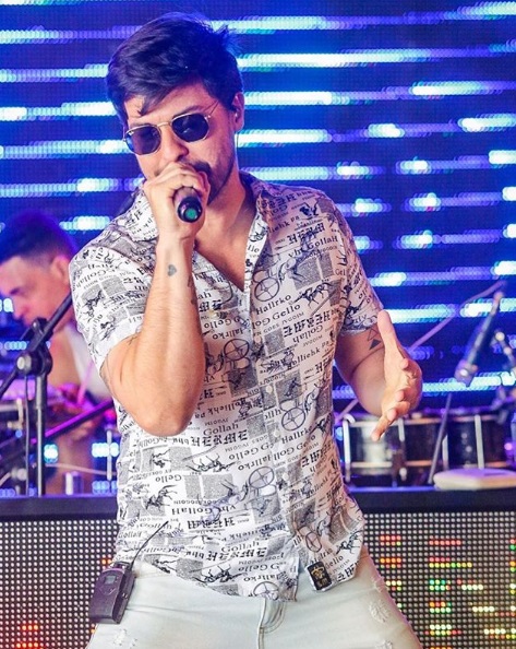 na imagem, o vocalista da banda isqueminha, Gabriel levy, cantando em um show